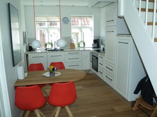 a kitchen with a wooden table and red chairs at Peder Dovns Slippe in Ribe