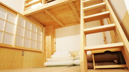 a loft bed in a room with a pile of towels at Poly Hostel 2 Namba in Osaka