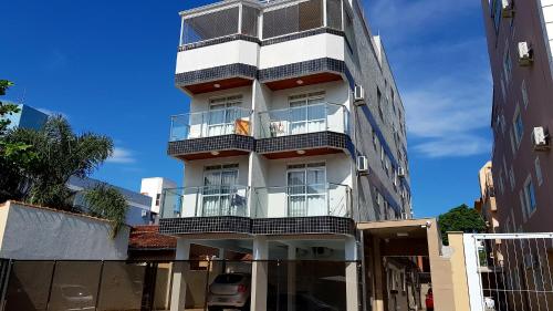 a tall white building with balconies on a street at Apartamento Residencial Messina in Florianópolis