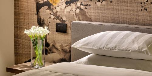 a vase with white flowers on a table next to a bed at Hotel The Cube in Fidenza
