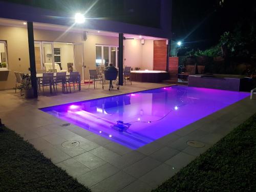 a pool with purple lights in a backyard at night at Umhlanga Lodge in Durban