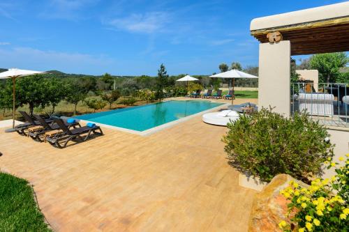 a swimming pool with chairs and umbrellas in a yard at Villa Luna in Sant Joan de Labritja