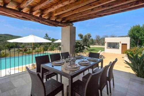 a dining table and chairs on a patio with a pool at Villa Luna in Sant Joan de Labritja