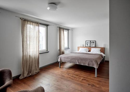 a bedroom with a bed and two windows at 2 Baloži in Kuldīga