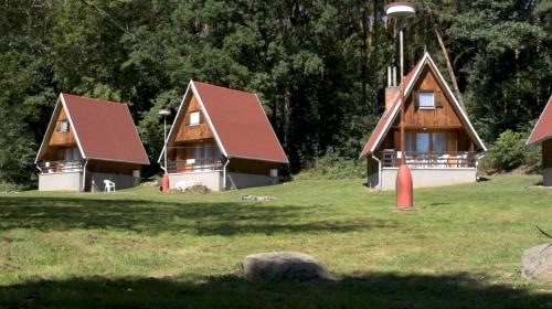 un grupo de tres casas en un campo de hierba en Barrandovská Zátoka en Kožlí u Orlíka