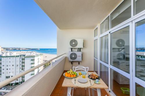 a balcony with a table with fruit and a view of the beach at Water Green House - Praia da Rocha in Portimão