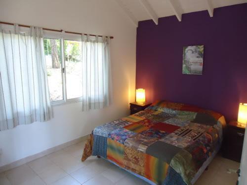 1 dormitorio con cama y pared púrpura en casa mandarina en Mar de las Pampas