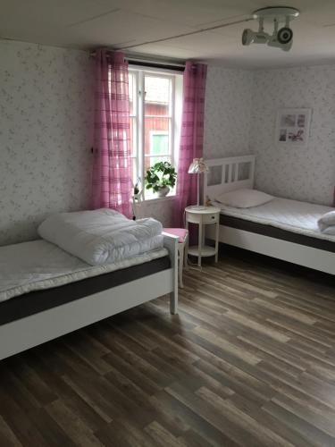 a bedroom with two beds and a window with pink curtains at Rolösa in Hjo