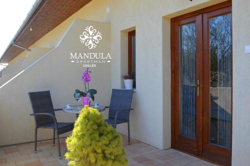 a patio with a table and chairs and a door at Mandula Apartman in Cegléd