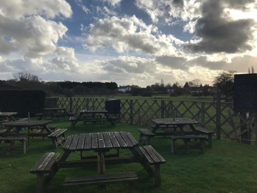 a group of picnic tables in a field with a fence at The Black Bull Inn in Fyfield