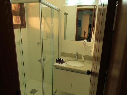 een badkamer met een wastafel en een glazen douche bij AP Beira da Lagoa da Conceição in Florianópolis
