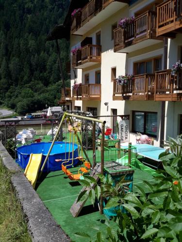 a playground in front of a apartment building at Hotel Ortles Dolomiti Walking & Spa in Cogolo