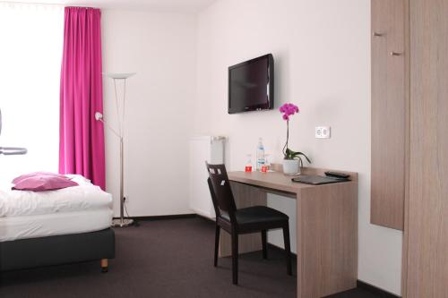 a hotel room with a desk with a bed and a tv at RheinHotel ARTE in Remagen