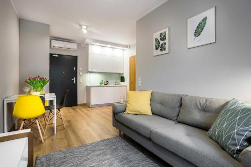 Una sala de estar con un sofá y una cocina. en UNIC Apartments Dominikańska, en Poznan