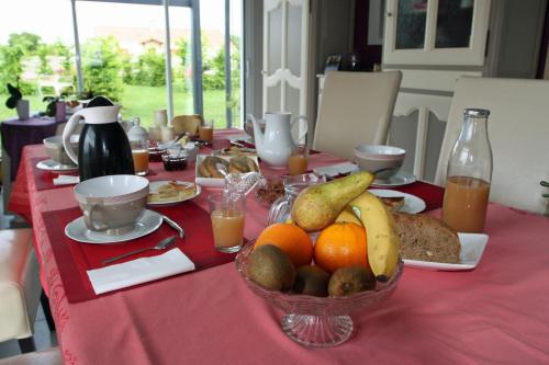 ein Tisch mit einer Obstschale auf einer roten Tischdecke in der Unterkunft Les 3 Vallées in Saint-Florent-le-Vieil