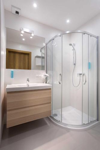 a bathroom with a glass shower and a sink at UNIC Apartments Dominikańska in Poznań