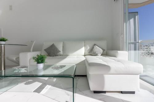 uma sala de estar com um sofá branco e uma mesa de vidro em Playa Honda 1A008 em Playa de las Americas