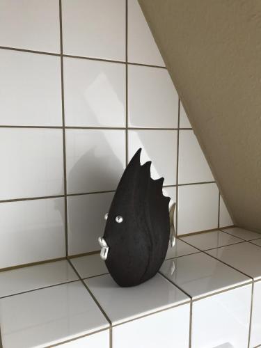 a black fish vase sitting on a tiled floor at Quartier 1903 in Oldenburg