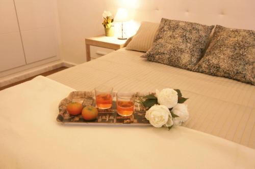 カルモナにあるApartamento Vacacional Carmonaのベッドの上にフルーツ、ドリンク、花をトレイ
