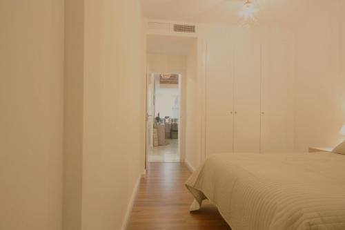 Dormitorio blanco con cama y pasillo en Apartamento Vacacional Carmona, en Carmona