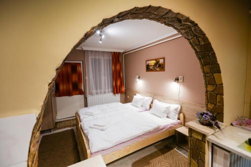 a bedroom with a large bed in an archway at Lara Apartman in Kisvárda