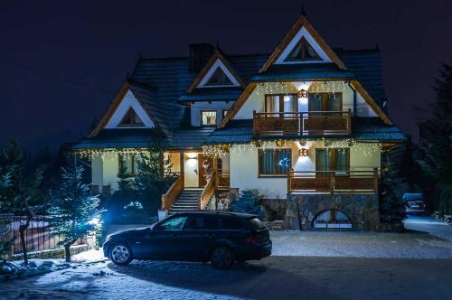 a car parked in front of a house with christmas lights at Sichlański Dworek & SPA in Murzasichle
