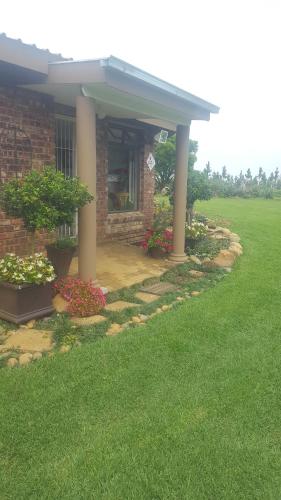 a brick house with two columns and flowers in a yard at Forest Hill Country Lodge in Piet Retief