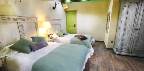 a bedroom with two beds with green and white at Alondra Hotel Boutique in Mineral del Monte