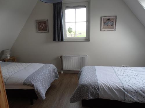 a bedroom with two beds and a window at Vakantiehuis het Neerland in Biggekerke