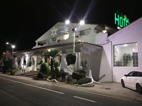 a white building with a car parked in front of it at Hotel Restaurante Santa Cruz in Santa Cruz de Mudela