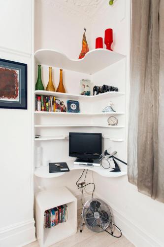 a room with white shelves and a computer monitor at ItalianFlat - Shaldon in London