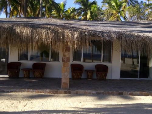 a house with chairs and a thatched roof at Hotel Rancho Buenavista in Los Barriles