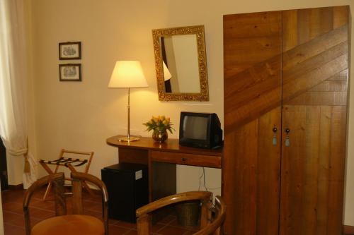 a room with a desk with a tv and a mirror at Hotel La Rocca in Gubbio