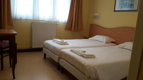 Dos camas en una habitación de hotel con toallas. en Stella Maris en Stella-Plage
