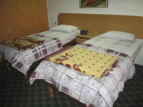 two beds in a hotel room with a blanket at Asia Hotel in Amman