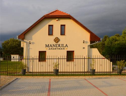 a large white building with a fence in front of it at Mandula Apartman in Cegléd