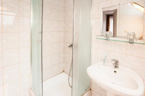 a white bathroom with a sink and a shower at Burg Vendégház in Eger