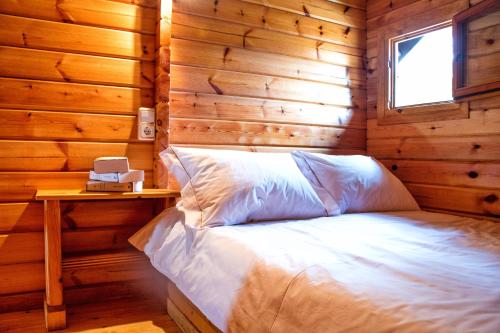 1 dormitorio con 1 cama en una cabaña de madera en Camping Preguntoiro en Sanxenxo