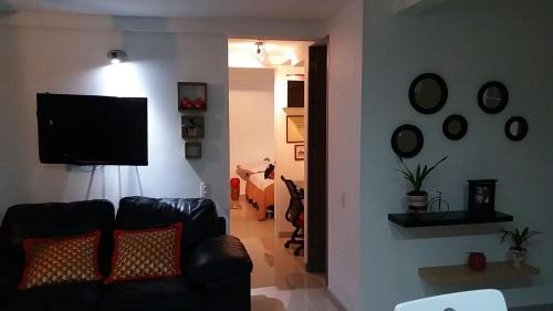 ein Wohnzimmer mit einem Sofa und einem Flachbild-TV in der Unterkunft Apartamento en colores y o cabaña hermosa in Medellín