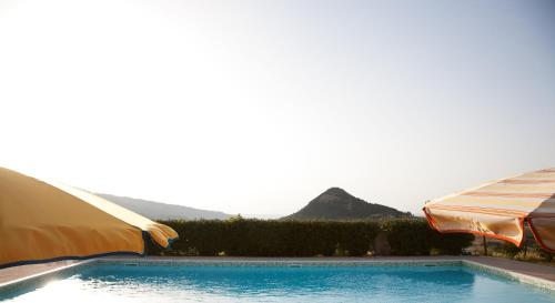 a swimming pool with an umbrella and a mountain at Agriturismo Villa Felice in Volterra