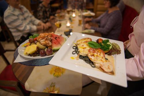 a person holding two plates of food on a table at Flair-Waldhotel Mellestollen in Saalfeld