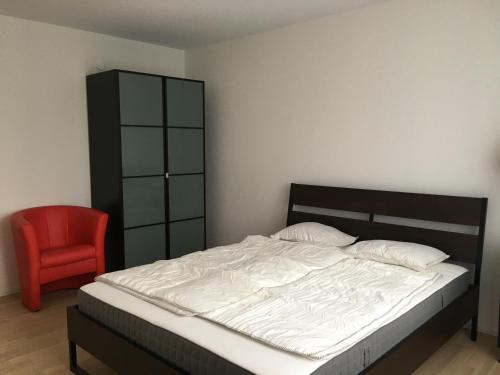 ein Schlafzimmer mit einem Bett und einem roten Stuhl in der Unterkunft Close to Zürich centre and Airport in Kloten