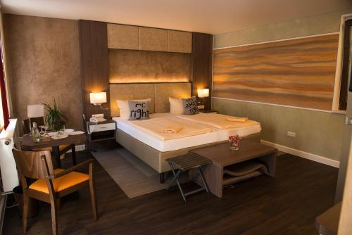 a bedroom with a bed and a table and a desk at Flair-Waldhotel Mellestollen in Saalfeld