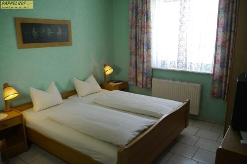 una camera da letto con un letto con lenzuola bianche e due lampade di Hotel Pappelhof a Weidenbach