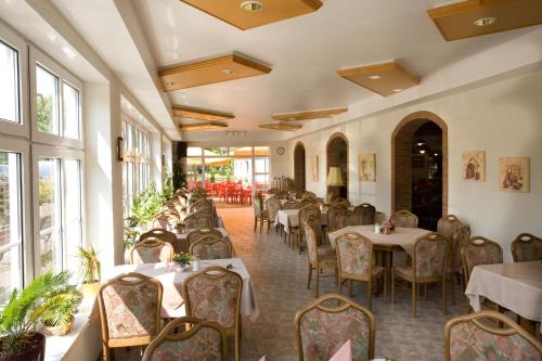 uma sala de jantar com mesas, cadeiras e janelas em Hotel Pappelhof em Weidenbach