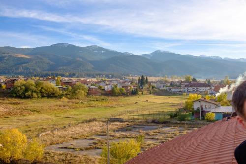 a person standing on a roof looking at a town with mountains at Atanasovata Kashta in Govedartsi