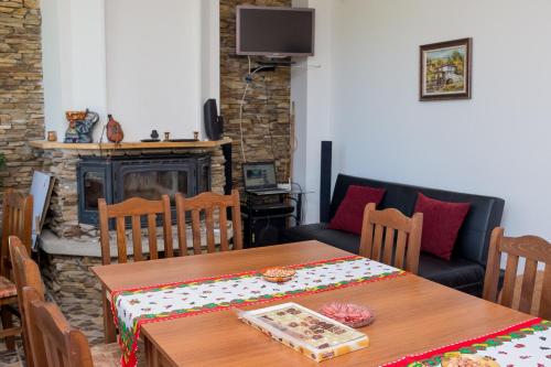a dining room with a table and a fireplace at Atanasovata Kashta in Govedartsi