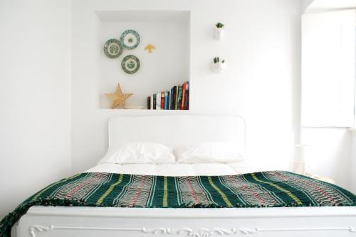 a bedroom with a white bed with a colorful blanket at Casa do Meio in Coimbra