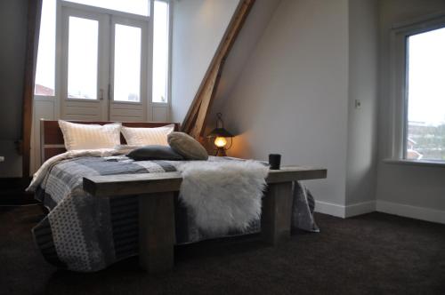 een slaapkamer met een bed met een bank en ramen bij Villa Kakelbont in Leeuwarden