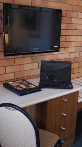 a laptop computer sitting on a desk with a tv at Ningana Motel in Mudgee